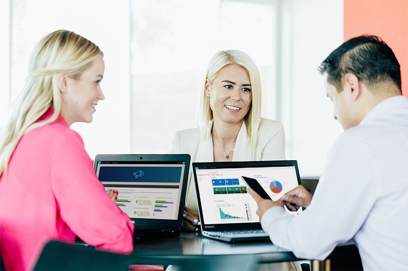 Jetzt wechseln und sparen 3 Personen im Büro mit 2 Laptops und einem Smartphone