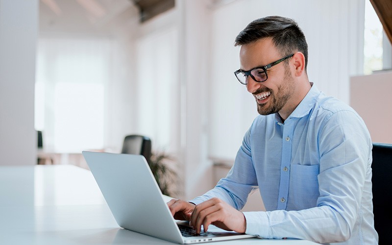 HCI improves IT operational efficiency to help manage the growing complexity. Man smiling while working on a laptop